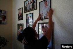 Belkis Martínez cuelga una fotografía de su hijo, que desapareció en una embarcación en algún lugar entre Cuba y el sur de Florida, Palma Sola, Cuba, 19 de junio de 2024. REUTERS/Alexandre Meneghini