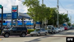 Varios vehículos hacen largas filas en una gasolinera en la ciudad de Miami. 