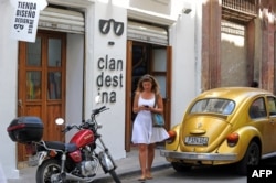 Una mujer camina frente a Clandestina, tienda privada en La Habana.