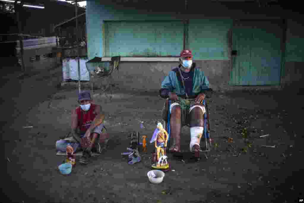 Seguidores de San Lázaro, con máscaras, en medio de la pandemia de coronavirus, rezan durante la peregrinación al santuario del santo para su fiesta anual, en el barrio El Rincón de Santiago de Las Vegas. (AP Photo/Ramon Espinosa)