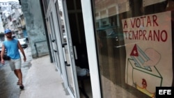 Un hombre camina frente a un cartel que invita a los vecinos a votar temprano en las elecciones para delegados municipales del Poder Popular en Centro en La Habana (Cuba).