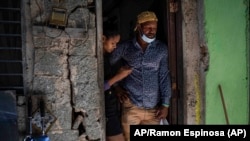  Emilio Román, padre de dos jóvenes y una hija que se encuentran en prisión acusados de participar en las recientes protestas contra el gobierno, posa con su nuera María Carla Milan Ramos en su casa en el barrio habanero La Güinera. 