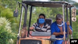 Dos cubanos viajan el martes en tractor por una calle de La Habana (Yamil Lage/AFP).