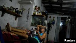 Una mujer se sienta con su perro en su casa durante un apagón el 22 de agosto de 2024. REUTERS/Norlys Perez