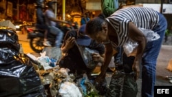 Varias personas buscan comida entre bolsas de basura en Caracas.