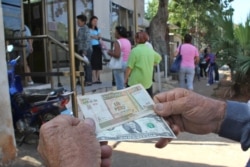 Un hombre muestra un peso convertible cubano y un dólar estadounidense frente a una oficina de la Western Union en La Habana (Foto: Archivo).