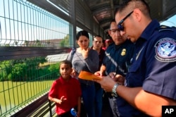 Funcionarios de Frontera procesan a una familia cubana en el Puente Internacional de Nuevo Laredo, Texas el 10 de julio de 2019 (Foto AP /Salvador González).