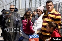 Un grupo de cubanos esperan ante agentes de seguridad de frontera en Ciudad Juárez.