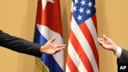 Con las banderas de Estados Unidos y Cuba como telón de fondo, el presidente Obama, a la izquierda, y el dictador Raúl Castro hacen un gesto durante una conferencia de prensa tras una declaración conjunta en La Habana, Cuba, el lunes 21 de marzo de 2016. (Foto AP/Dennis River)