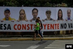 Transeúntes caminan frente a una valla en rechazo a la Asamblea Constituyente.