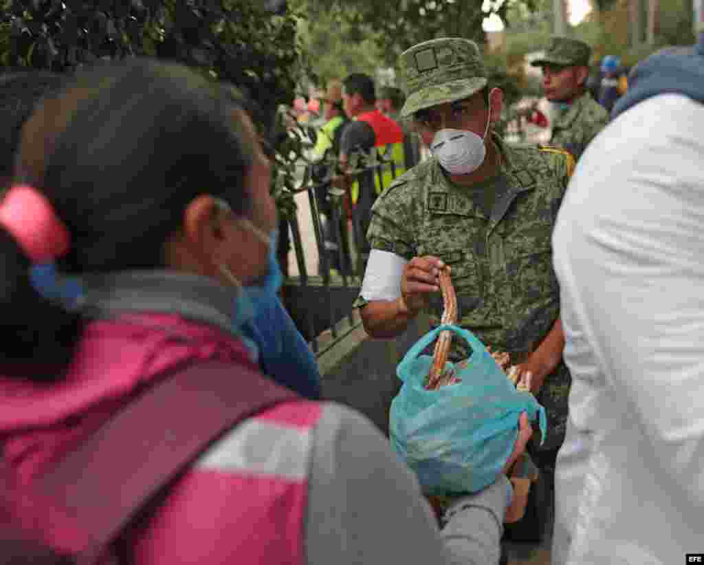 Una joven ofrece comida a brigadistas y voluntarios que continúan con las labores de rescate en los edificios colapsados por el sismo.