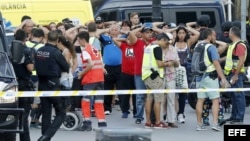 Un grupo de gente con los brazos en alto ante el despliegue policial en el lugar del atentado ocurrido hoy en las Ramblas de Barcelona.