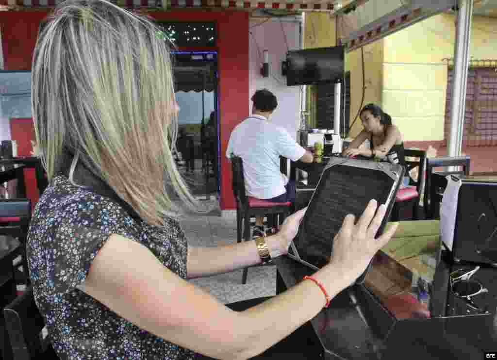 Una joven observa el menú en una tableta en un restaurante de La Habana. 