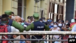 Policías controlando la población en una cola para conseguir alimentos, en La Habana.