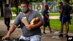 Un hombre carga el pan mientras viaja en bicicleta por una calle de La Habana. (AP/Ramon Espinosa)