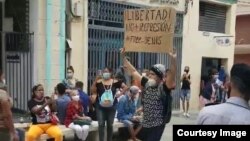 Joven con cartel protesta en el bulevar de San Rafael, La Habana.