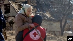 Un trabajador de la Cruz Roja traslada a una anciana durante la evacuación de Irpín, a unos 25 kms (16 millas) al noroeste de Kiev, el 11 de marzo de 2022. (AP Foto/Efrem Lukatsky)