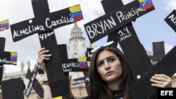 Manifestantes cargan cruces negras con el nombre de los muertos en las protestas en Venezuela durante una protesta este domingo en la Plaza San Pedro, en el Vaticano.