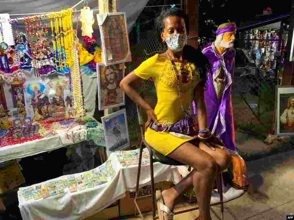 Una vendedora de imágenes religiosas espera a los clientes durante la procesión de San Lázaro,&nbsp; en El Rincón, La Habana, Cuba, el 17 de diciembre de 2020. (Foto de ADALBERTO ROQUE / AFP)