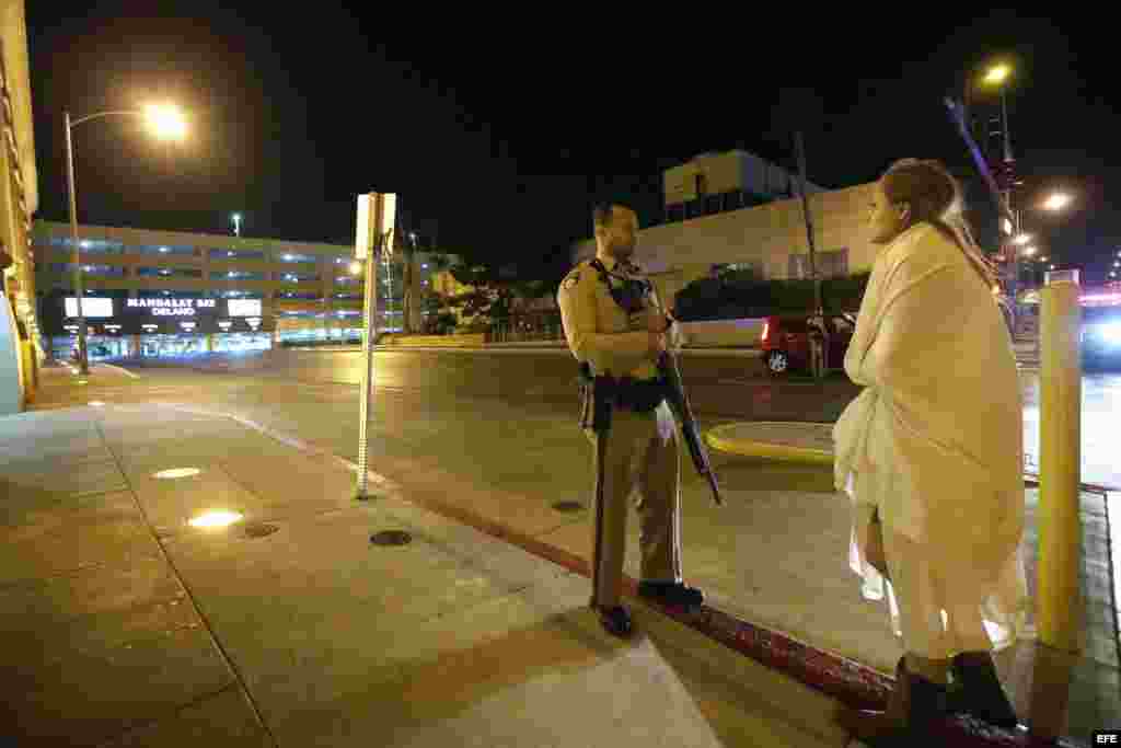 Un agente de policía permanece en guardia junto a una mujer envuelta en una manta, ante el hotel Mandalay Bay, cerca de donde se produjo el tiroteo. 