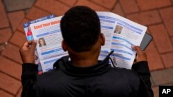 Un hombre lee material electoral antes de votar durante el último día de votación anticipada, el sábado 2 de noviembre de 2024, en Charlotte, Carolina del Norte (Foto AP/Mike Stewart)