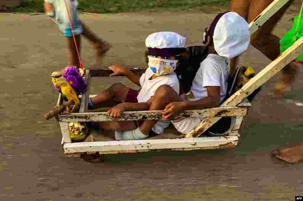 Niños son empujados por sus padres en una carretilla durante la procesión de San Lázaro en El Rincón.(Foto de ADALBERTO ROQUE / AFP)