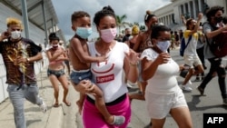 Una mujer con un niño en brazos marcha frente al Capitolio de La Habana durante una manifestación contra el presidente cubano Miguel Díaz-Canel en La Habana, el 11 de julio de 2021.