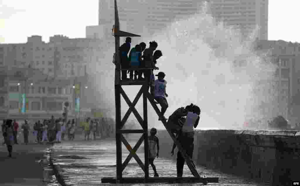 Varios niños juegan en la obra "Salvavidas" del artista Duvier Del Dago expuesta en el Malecón hoy, domingo 24 de mayo, donde ha sido inaugurada la exposición "Detrás del Muro" como parte de la XII Bienal de Arte de La Habana.