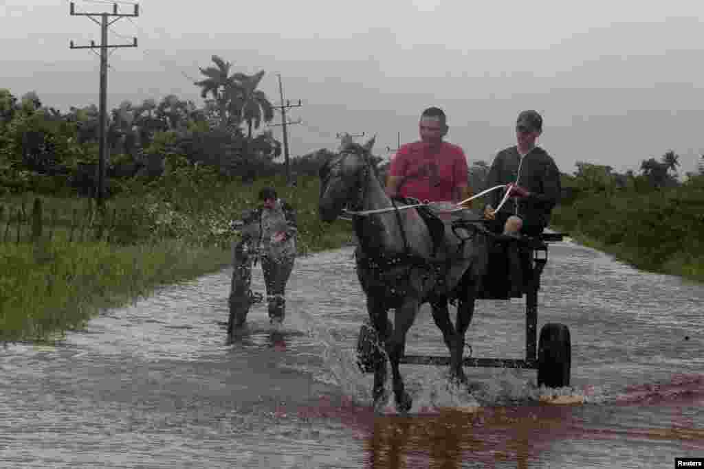 Los hombres viajan en su carro tirado por caballos por una carretera inundada mientras el huracán Helene pasa cerca de la costa cubana, en Pinar del Río, Cuba, el 25 de septiembre de 2024. REUTERS/Stringer