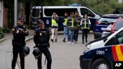 Policías montan guardia mientras otros agentes con chalecos amarillos caminan hacia atrás junto a la embajada de Ucrania en Madrid, el miércoles 30 de noviembre de 2022. (AP Foto/Paul White)