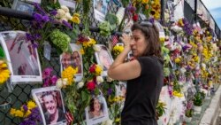 Gini Gonte visita el miércoles 7 de julio de 2021 un muro con fotografías y flores para recordar a las víctimas del desplome del edificio residencial Champlain Towers South, en Surfside, Florida. (Al Diaz/Miami Herald vía AP)