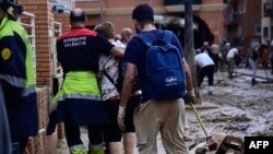 Un bombero abraza a una mujer mientras continúan los trabajos para limpiar los escombros de las casas y las calles en Alfafar, en la región de Valencia.