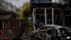 Personas revisan el daño a una tienda destruida un día antes durante un ataque ruso en Jersón, Ucrania, el viernes 25 de noviembre de 2022. (AP Foto/Bernat Armangue).